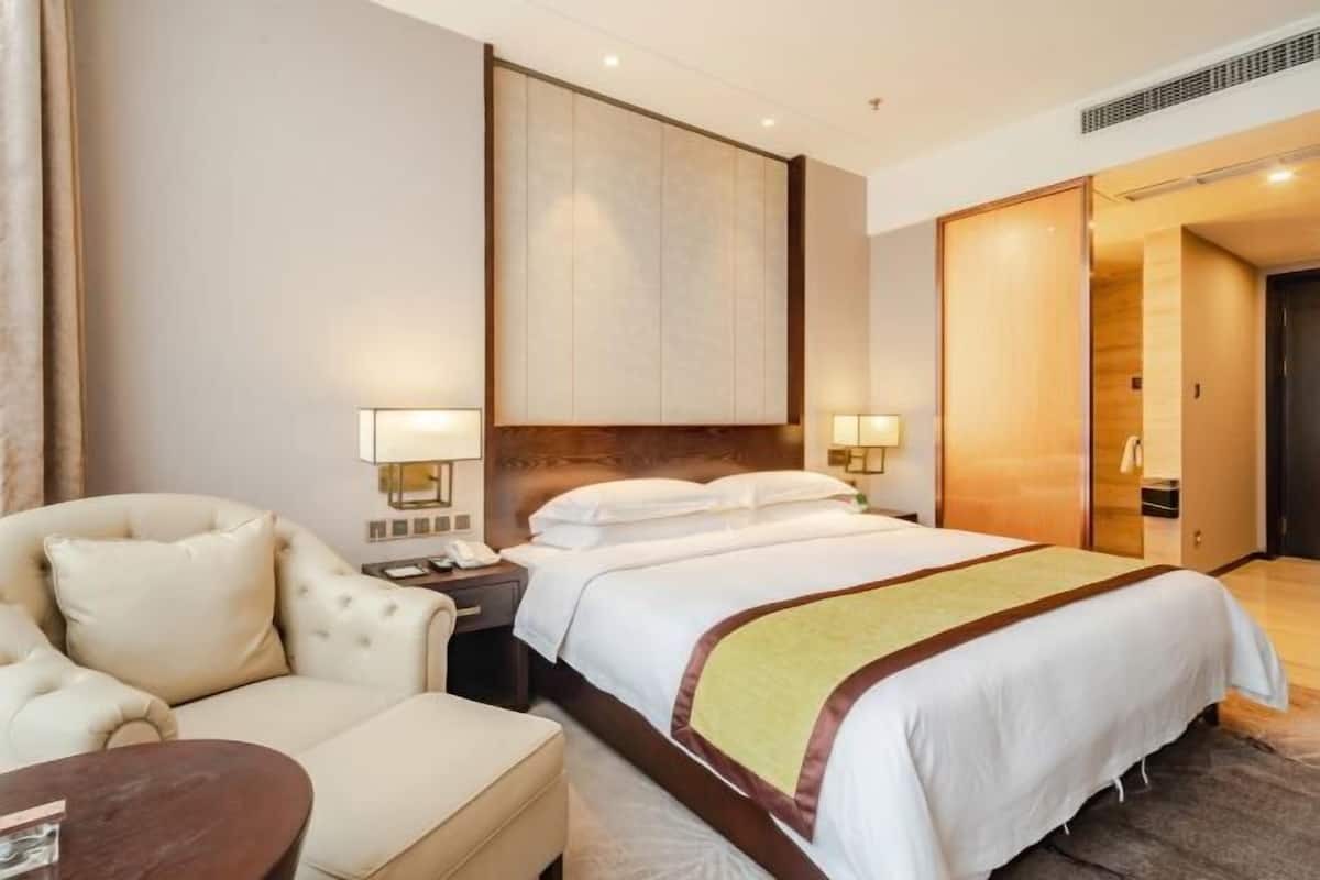 Ein Hotelzimmer mit Bett, Sessel, Schreibtisch und Kleiderschrank.