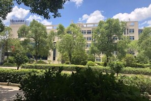 A building with multiple floors, surrounded by greenery and trees. - Yoron Hotel (Nanchang County)