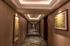 A hotel hallway with a carpeted floor, framed artwork on the walls, and a ceiling with recessed lighting. - Yoron Hotel (Nanchang County)