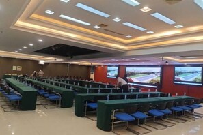 A conference room with rows of tables and chairs, a large screen, and a projector. - Yoron Hotel (Nanchang County)