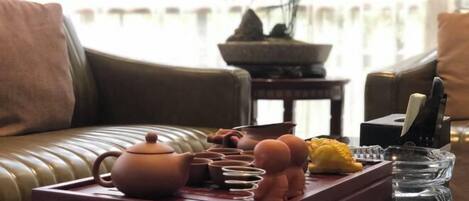 A cozy living room with a leather sofa, a wooden coffee table with a teapot, cups, and a small figurine.