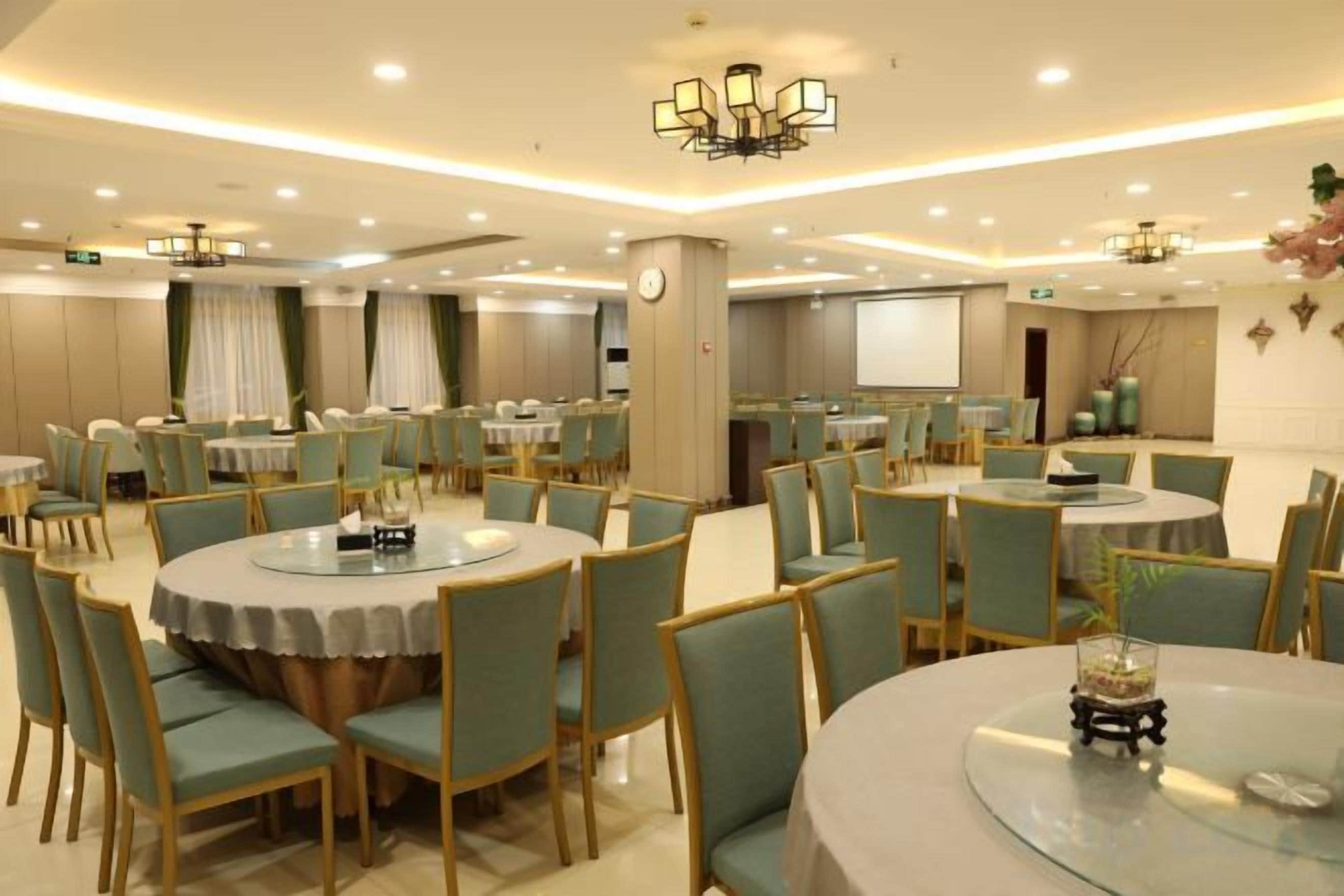 A conference room with multiple tables and chairs, a projector screen, and a clock on the wall.