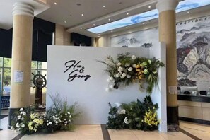 A reception area with a white backdrop, floral arrangements, and a sign that reads 'Flug & Gong.' - Yoron Hotel (Nanchang County)