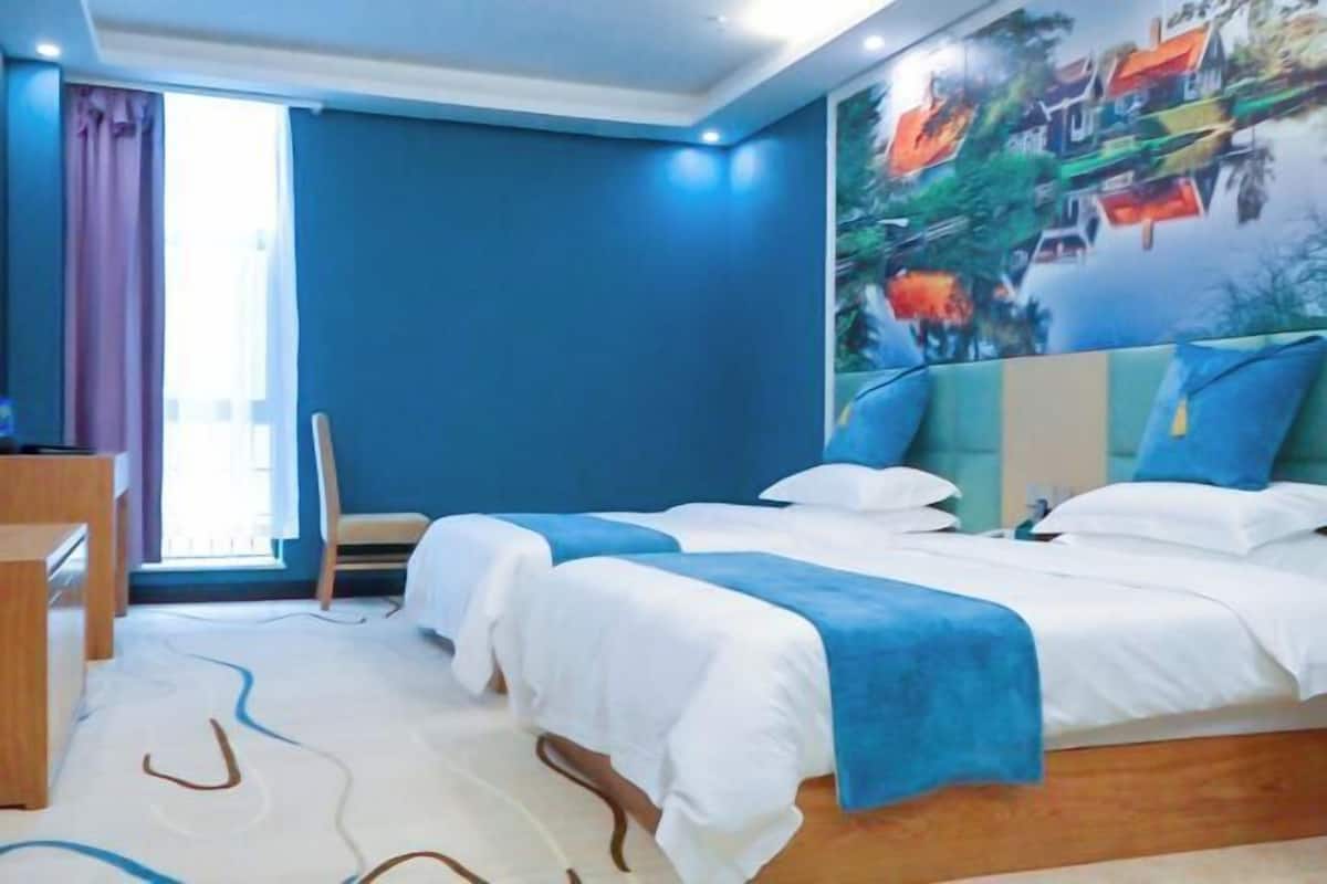 Een hotelkamer met een groot bed, een bureau en een raam met gordijnen.