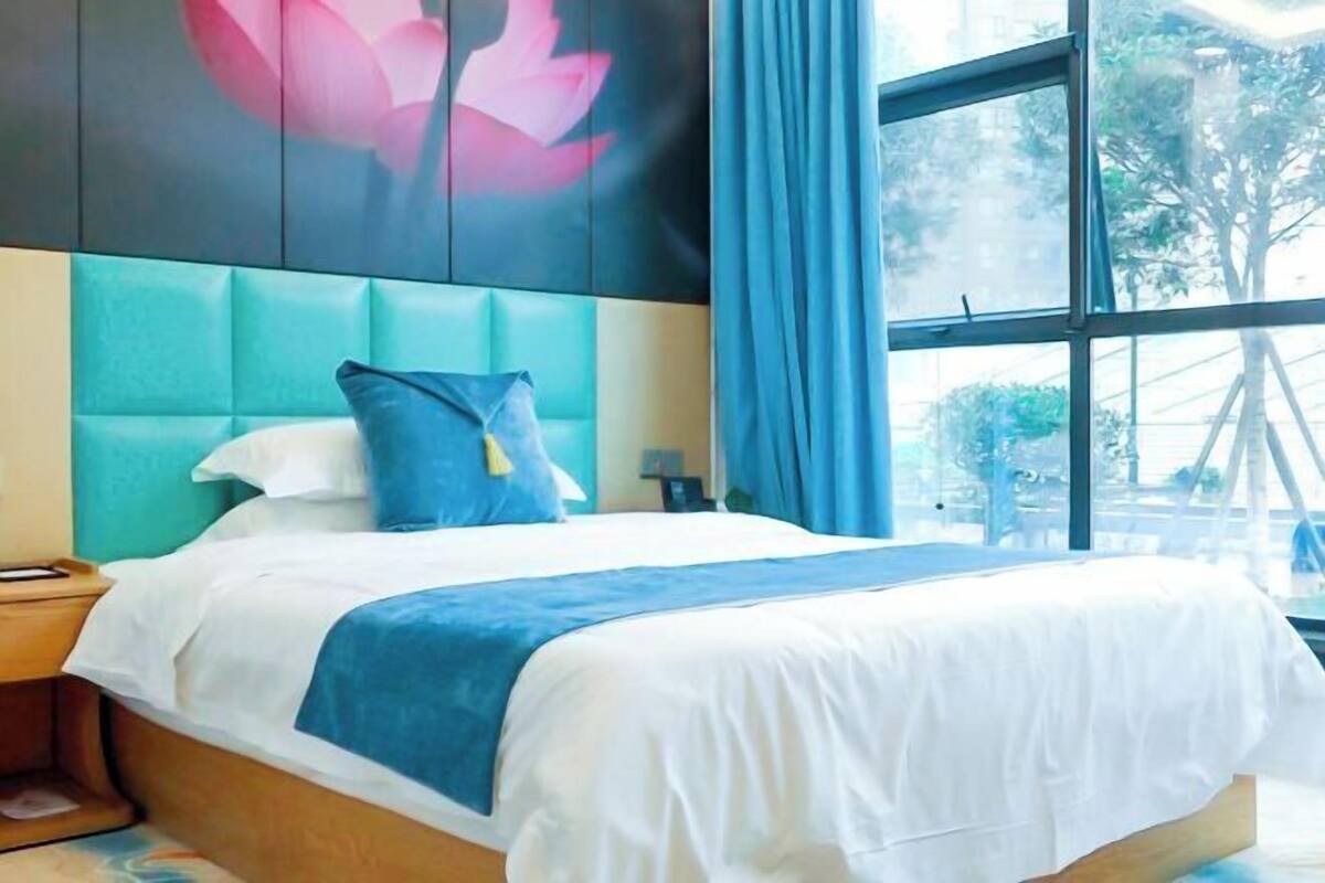Een slaapkamer met een bed, nachtkastje, wanddecoratie en een raam met gordijnen.