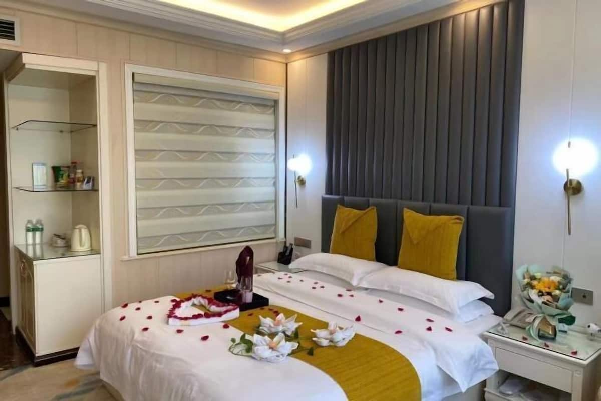 Een hotelkamer met een bed, nachtkastje en een spiegel.