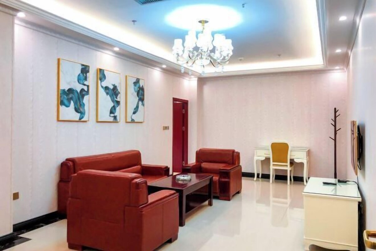 A modern living room with red leather sofas, a coffee table, a dining table with chairs, and artwork on the walls.