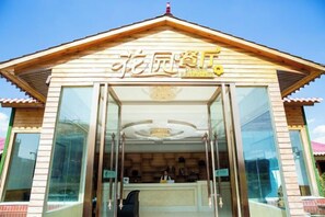 A building with a traditional architectural style, featuring a prominent entrance with glass doors and a sign above. - Yibo Garden Hotel (Zhenxiong)
