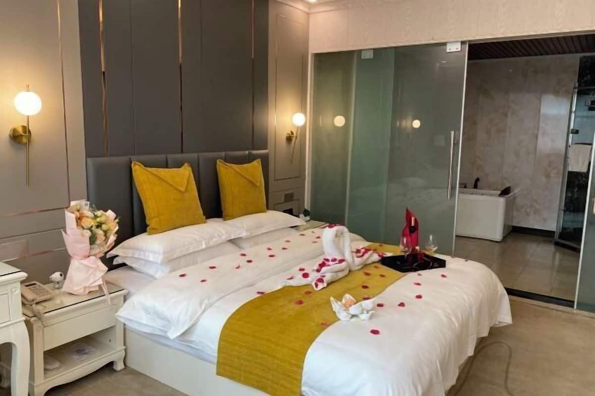 Een hotelkamer met een bed, nachtkastje en een glazen scheiding.