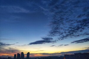 A city skyline at dusk with high-rise buildings silhouetted against a sunset sky.
