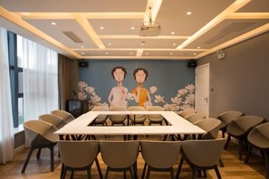 A conference room with a long table, multiple chairs, a projector, and a mural on the wall. - Magnolia Hotel (Rizhaogang Lighthouse Scenic Area Lianyungang Road) (Rizhao)