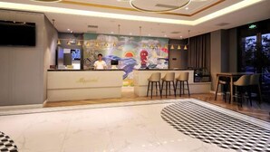 Un moderno vestíbulo de hotel con recepción, zona de bar y asientos.