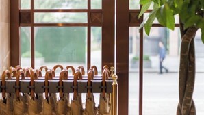 Une fenêtre avec un porte-parapluies en métal où sont rangés plusieurs parapluies.