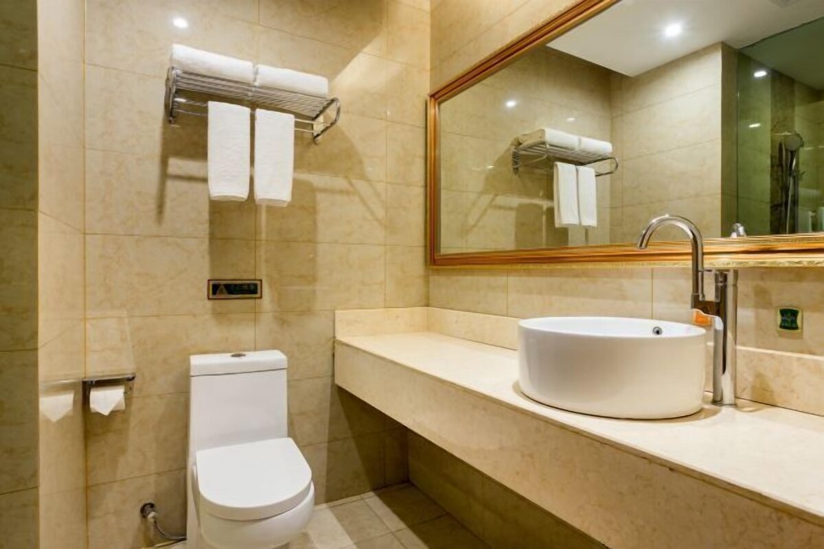 Un baño moderno con inodoro, lavamanos y espejo.