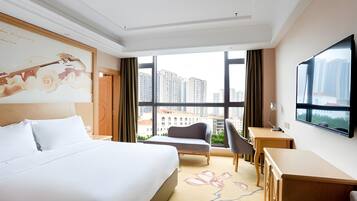 A hotel room with a large bed, a desk, a chair, and a TV.