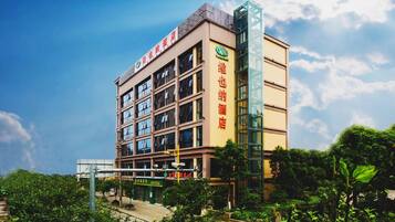 A multi-story hotel with a modern design, featuring a prominent glass elevator shaft and multiple balconies.