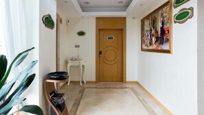 Un pasillo de hotel con una puerta de madera, una mesita con un cuenco y un cuadro en la pared.