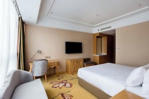 Una habitación de hotel con una cama, un escritorio, una silla, un televisor y un armario.