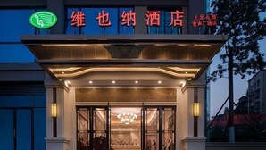 Entrada de hotel de diseño moderno, con un cartel llamativo con caracteres chinos y un logotipo verde sobre la entrada.