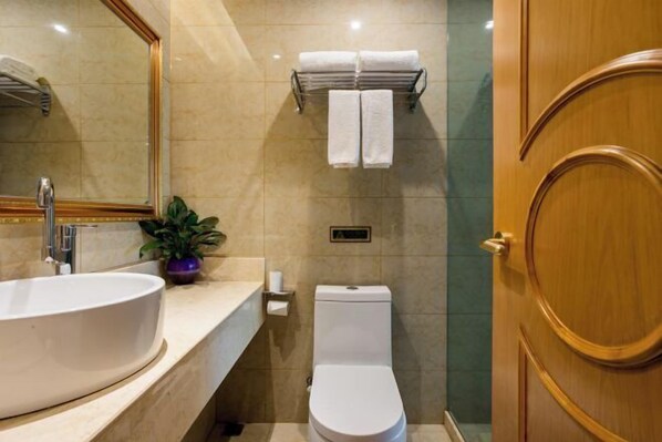 Ein Badezimmer mit einem großen Waschbecken, einer Toilette, einem Spiegel und einem Handtuchhalter.