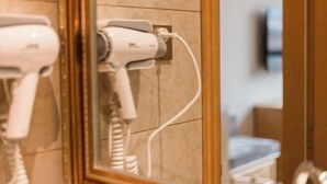 A bathroom with a hairdryer plugged into a wall socket, a mirror, and a towel rack. - Vienna Hotel (Chongqing Dazu Stone Carving) (Chongqing)
