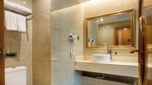 Une salle de bain moderne équipée de toilettes, d’un lavabo, d’un miroir et d’un sèche-cheveux.