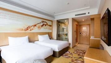 Habitación de hotel con dos camas, un espejo grande y un televisor.