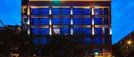 A multi-story hotel with a modern facade, illuminated signage, and a prominent entrance.