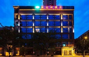 Un hotel de varios pisos con fachada moderna, señalización iluminada y una entrada destacada.