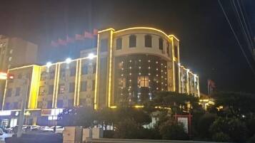 Un edifici de diverses plantes amb façana corba i finestres il·luminades de nit.