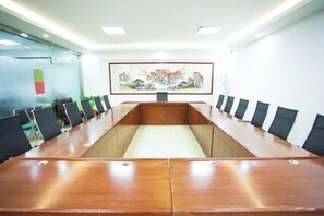 A conference room with a long table, chairs, and a painting on the wall. - Jucheng Youpin Hotel (Ju County)