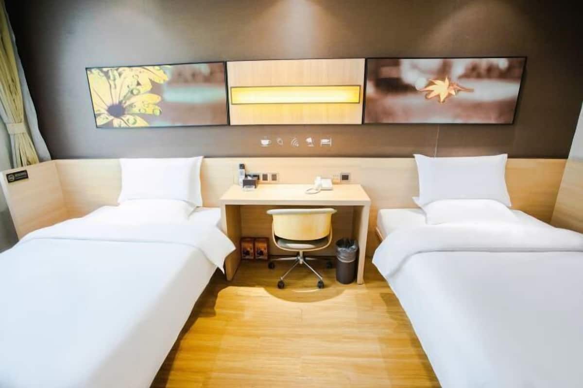 Une chambre d’hôtel avec deux lits, un bureau, une chaise et une poubelle.