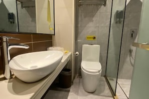 A bathroom with a white sink, toilet, and glass shower enclosure. - Jucheng Youpin Hotel (Ju County)