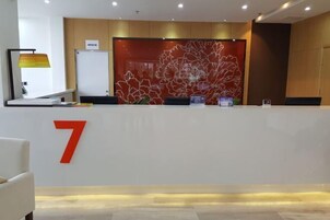 A reception desk with a large number '7' on the wall, a modern lamp, and a decorative wall piece.