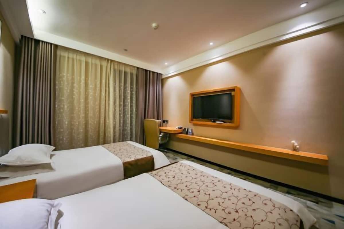 Una habitación de hotel con dos camas, un televisor en la pared, un escritorio y una silla.