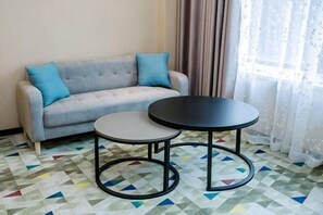 A room with a sofa, two tables, and a patterned floor. - Mingcheng Boutique Hotel in Bengbu City (Bengbu)
