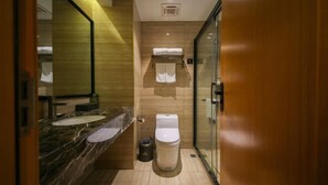 Un baño moderno con lavamanos de mármol, inodoro y cabina de ducha de vidrio.