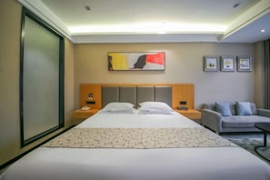 A hotel room with a large bed, a sofa, a nightstand with a phone, and a painting on the wall. - Mingcheng Boutique Hotel in Bengbu City (Bengbu)