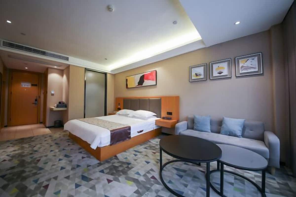 Una habitación de hotel con una cama, un sofá, una mesa redonda y una pared decorada con cuadros.