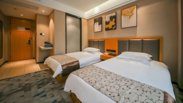 Habitación de hotel con dos camas, cabeceros, mesitas de noche y un cuadro en la pared, además de una puerta que da a otra habitación.