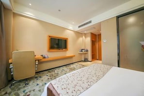 A hotel room with a bed, a desk, a chair, a television, and a bathroom door. - Mingcheng Boutique Hotel in Bengbu City (Bengbu)
