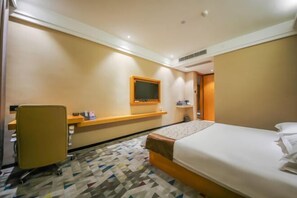 A hotel room with a bed, a desk, a chair, a TV, and a patterned carpet. - Mingcheng Boutique Hotel in Bengbu City (Bengbu)