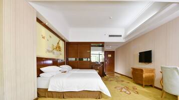 A hotel room with a large bed, a desk, a chair, a television, and a decorative wall.