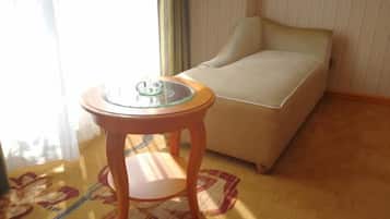 Ein Zimmer mit einem Bett, einem kleinen runden Tisch mit Glasplatte und einem gemusterten Teppich.