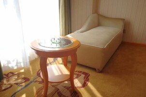 Una habitación con una cama, una mesita redonda con superficie de vidrio y una alfombra estampada.