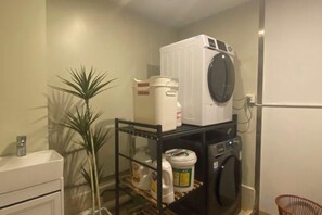 A laundry area with a washing machine, a dryer, and shelves with various items. - Zhongtian Cultural Hotel (Jieyang Tower) (Jieyang)
