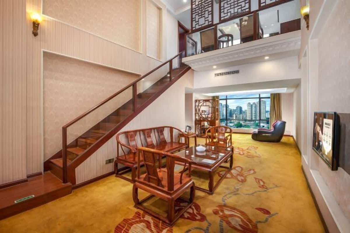 A spacious lobby with a staircase, wooden furniture, and a city view.