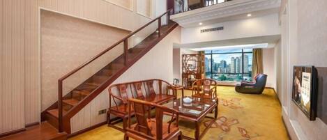 A spacious lobby with a staircase, wooden furniture, and a city view.