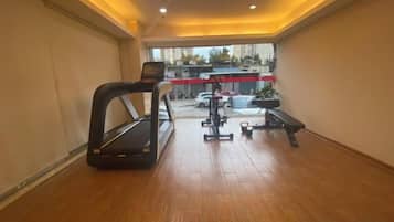 A gym with a treadmill, bench, and weights.