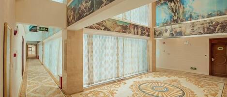 Un pasillo de hotel con suelo estampado, un mural grande en el techo y una puerta a la derecha.